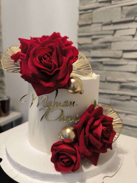 Gâteau blanc décoré de roses rouges et feuilles d'or